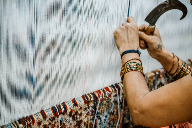 A close-up view of a skilled artisan weaving a traditional Indian carpet with precision. The artisan's hands delicately craft the intricate patterns that showcase cultural heritage and skilled craftsmanship.