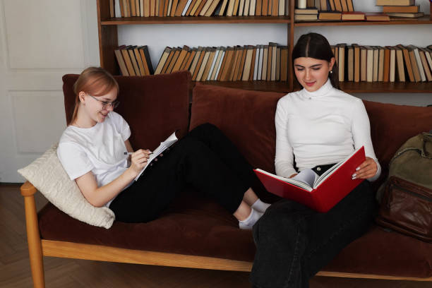 istock Students Collaborating on a Project in a Modern Library, two teenage girls  Discussion, Using Laptop and Books, Sharing Ideas and Laughing Together. 2195482264
