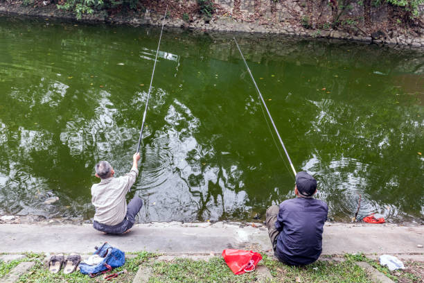 Hanoi, Vietnam - March 22, 2024: Two Vietnamese men fishing in Thien Quang Lake