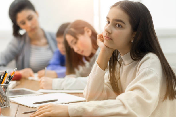 istock Upset school girl thinking, sitting at boring lesson 2195483236