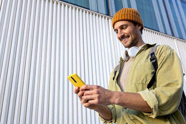 Smiling young man using smartphone on city street