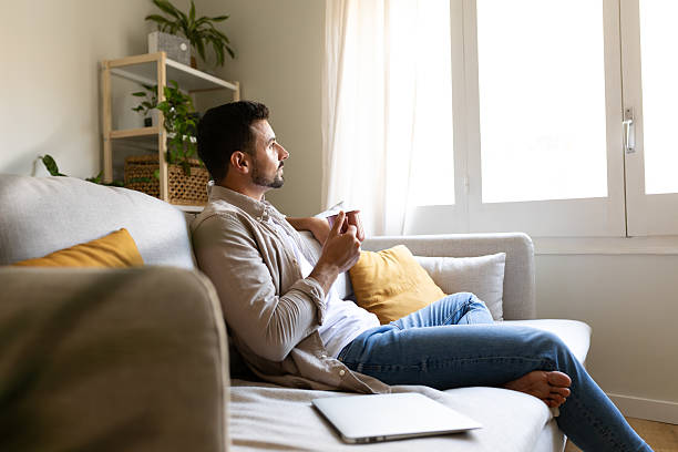 Young man relaxing on sofa with coffee, enjoying quiet moment at home