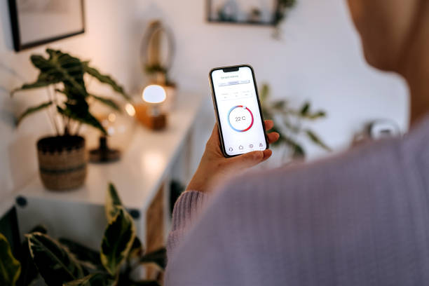 istock Woman setting up temperature on smart phone app at home 2195485476