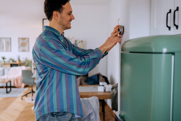 istock Young casually clothed man adjusts the temperature at home with a device on the wall 2195487976