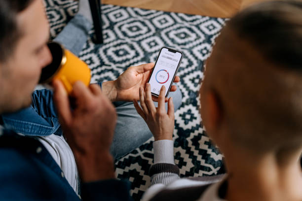 istock Couple adjusting temperature on smart phone app at home 2195488091