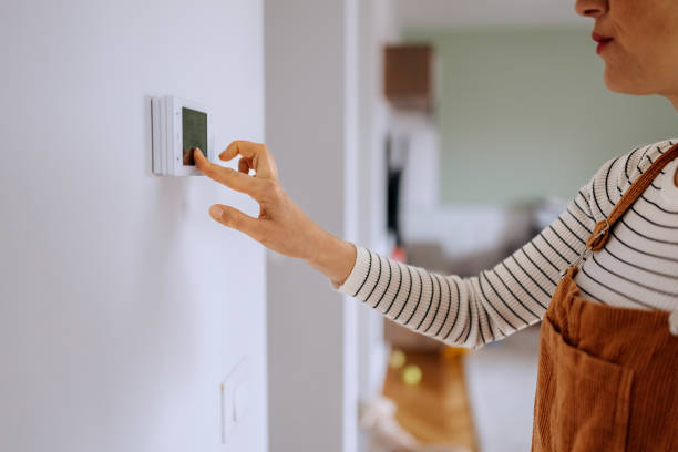 istock Casually clothed woman setting up temperature on smart thermostat at home 2195488183