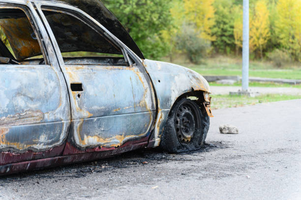 istock Burned car wreck abandoned on roadside in nature 2195493393