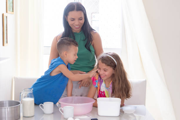istock brothers preparing cake with mother putting flour on their faces 2195494250