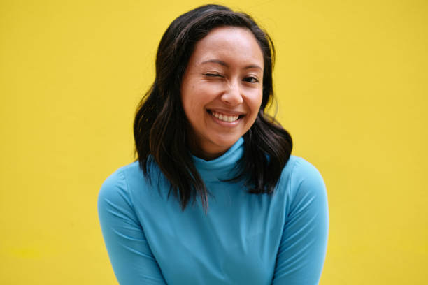 istock Young woman winking and smiling on yellow background 2195495161