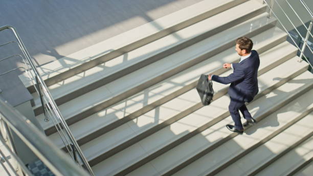 istock Rich man climbing staircase modern building carrying briefcase. Determined man 2195496394