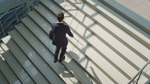 istock Entrepreneur walking stairs modern building holding briefcase. Confident ceo man 2195496461