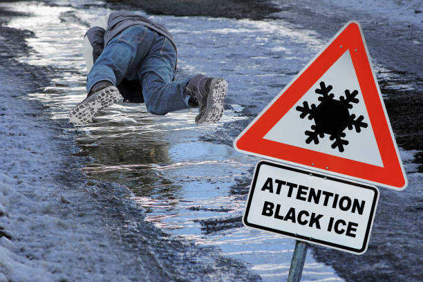 Sign with attention black ice on a sidewalk in winter. A man slips on black ice