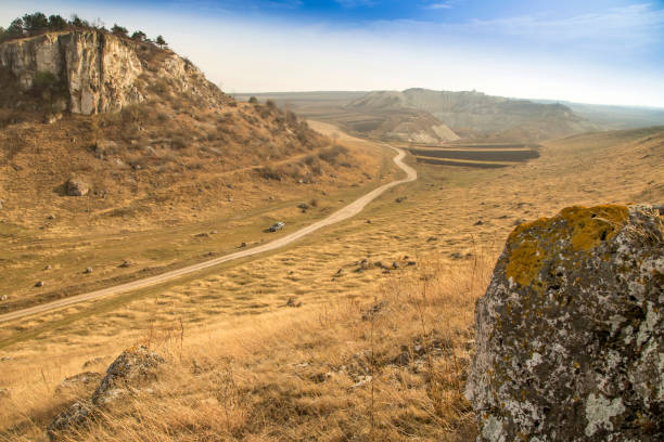 Rocky hills, fields and road: an autumn landscape under a blue sky