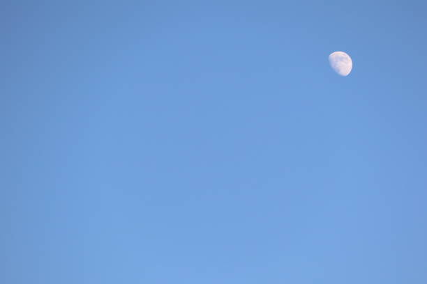 A serene and calming view of the beautiful moon appearing against a vibrant blue sky, ideal for naturethemed projects