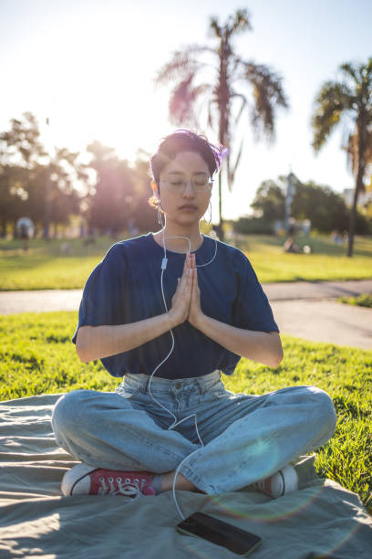 istock Young woman meditating in the park on a sunny evening 2195499096