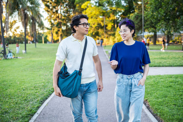 istock Young friends sharing a conversation while walking in a sunny park environment 2195499133