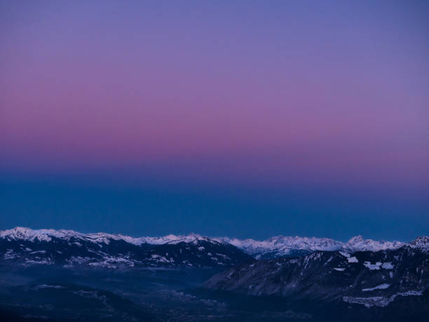 A serene winter landscape at dusk with a soft pink sky, snow-covered ground, and a peaceful, tranquil atmosphere.