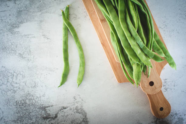 istock Green asparagus beans on wooden cutting board on concrete background, copy space. 2195500007