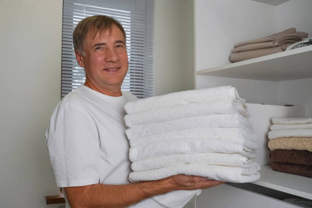 istock Man with stack of clean towels indoors 2195501154
