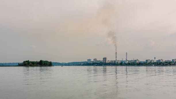 istock Industrial city skyline with smokestacks visible across a calm river 2195502841