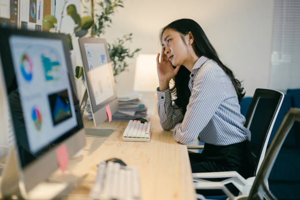 istock Young asian businesswoman is having a headache and feeling tired from working on a computer in the office, she is massaging her head to relieve the pain 2195503424