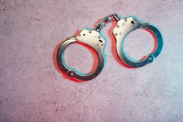 Handcuffs on concrete surface with police vehicle lighting