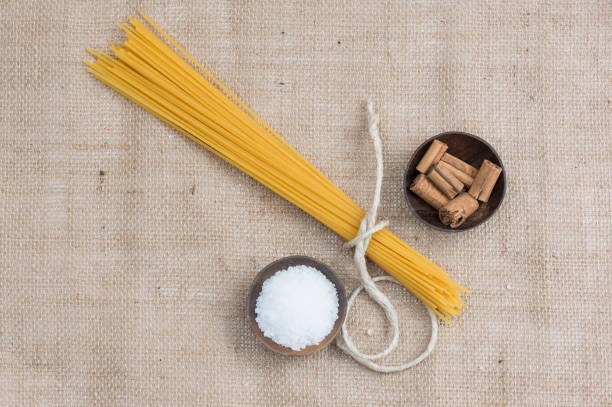 Two ears of wheat on a kitchen counter with raw spaghetti