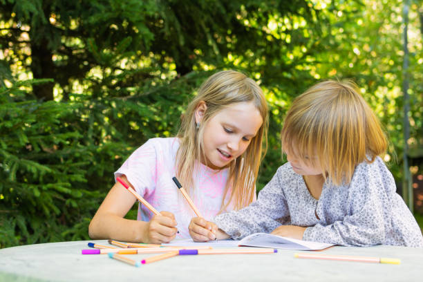 istock Siblings sharing a bonding moment while drawing in a sunlit garden 2195512931