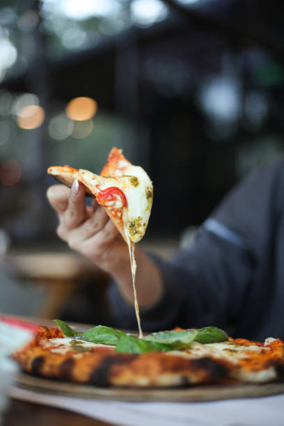 a pizza slice with the cheese dripping off, holding the pizza with its hand