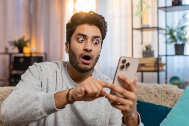 istock Happy man using smartphone scrolls through news on smartphone reacting with surprise and excitement 2195514526