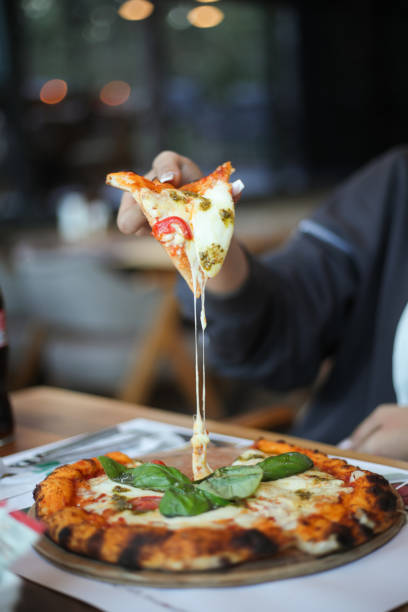 istock woman holding pizza with her hand 2195515091