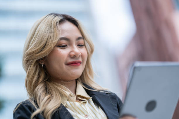Focused businesswoman using a stylus with a tablet in an urban setting. Showcasing modern technology, precision, and professionalism, ideal for innovation and productivity themes.