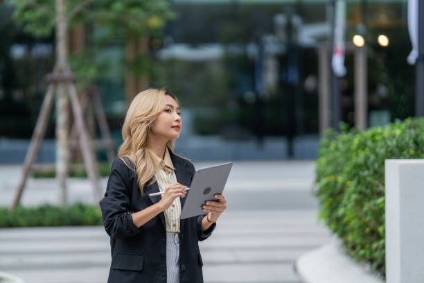 istock Focused businesswoman using a stylus with a tablet in an urban setting. Showcasing modern technology, precision, and professionalism, ideal for innovation and productivity themes. 2195515783