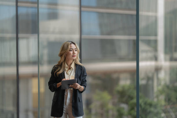 istock Professional woman using a tablet in a bright, modern workspace. Highlighting innovation, digital tools, and ambition within a serene urban setting for business inspiration. 2195519153