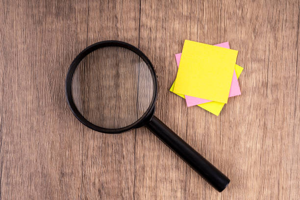 istock Magnifying glass and blank yellow adhesive note 2195521353
