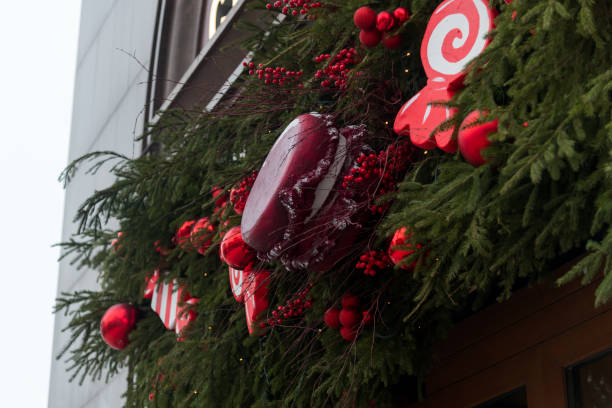 Festive holiday decoration with red ornaments and candy accents on a storefront in winter