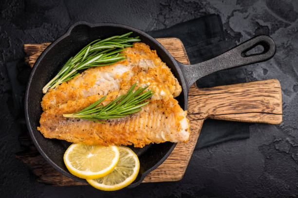 istock Pan Fried Hake white fish fillet. black background. top view 2195523303