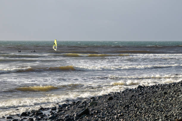 Jordan River, British Columbia, Canada - December 26 2024:  Windsurfer and surfers on a winter day playing in the surf.
