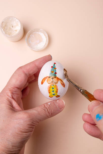 istock artist's hands paint an egg, close-up 2195525887