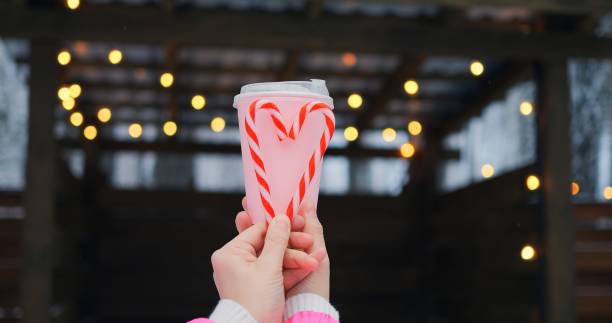 Gentle scene merges pink beverage and candy cane heart, reflecting warmth in subtle lights, as warmth permeates winter surroundings, granting warmth that resonates with heartfelt celebrations.