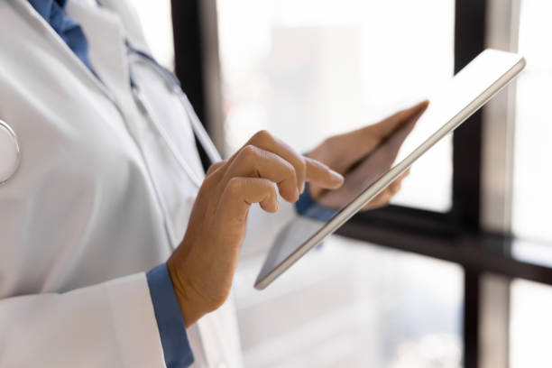 istock Closeup female therapist in white lab coat using modern tablet 2195529020