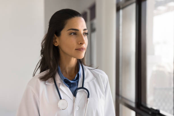 istock Thoughtful Brazilian female doctor looking out window 2195529949