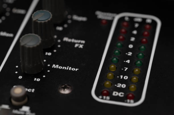 A detailed close-up of an audio mixer showing monitor knobs and LED level indicators. The image emphasizes the precision controls and visual feedback tools used in professional sound engineering.