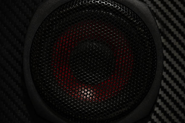 A detailed close-up of a speaker grille with red accents visible through the mesh. The image emphasizes the design and aesthetic of modern audio equipment.