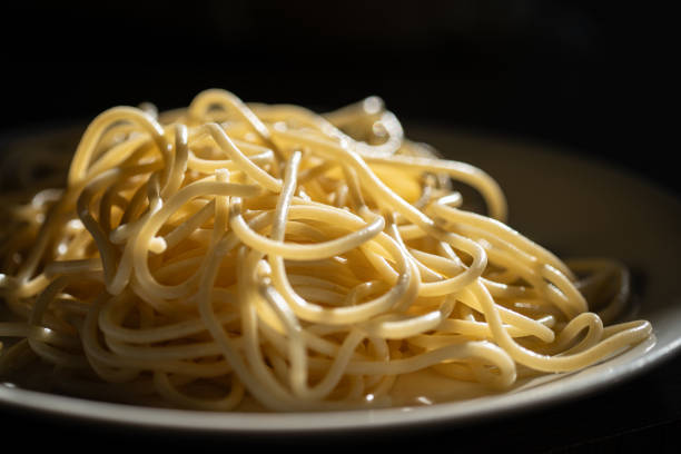 A close-up of freshly cooked spaghetti, glistening under natural light and ready to be served.
