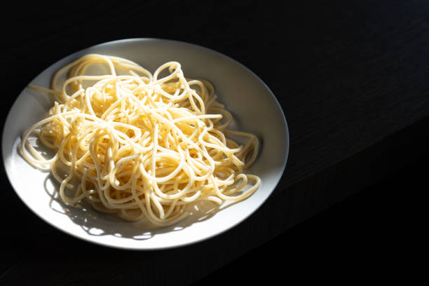 A close-up of freshly cooked spaghetti, glistening under natural light and ready to be served.
