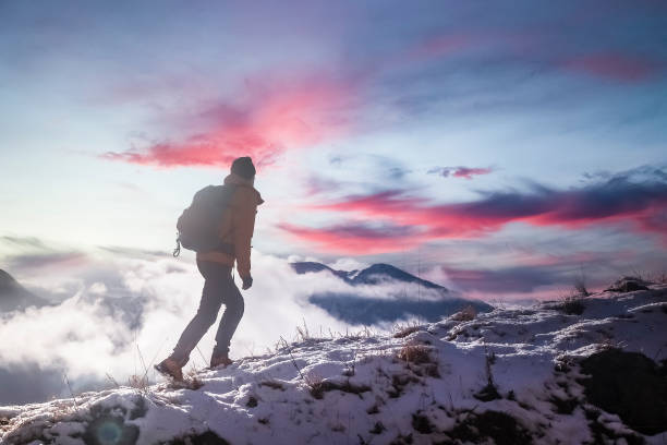 istock Hiker Walking Through Winter Mountains with a Fiery Sky 2195534376