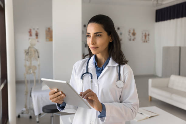 istock Latina therapist holding digital tablet standing in examination room 2195535089