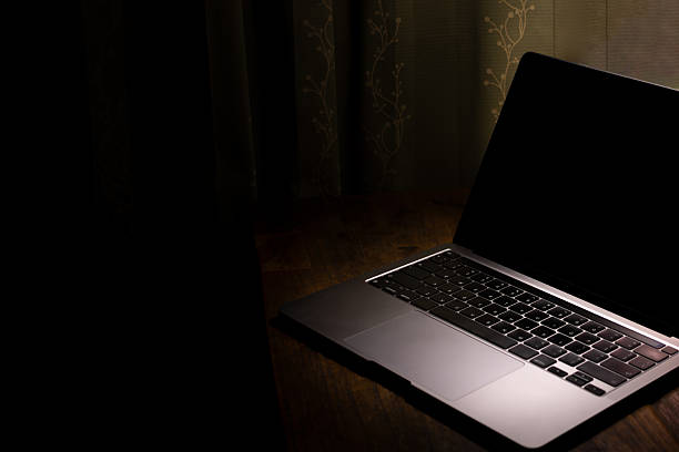 istock A laptop is open on a table in a dark room 2195538016