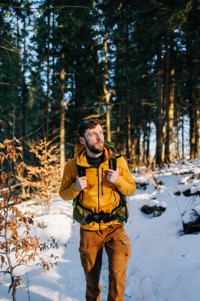 istock Handsome man hiking through the snowy footpath in the forest in spring 2195539640
